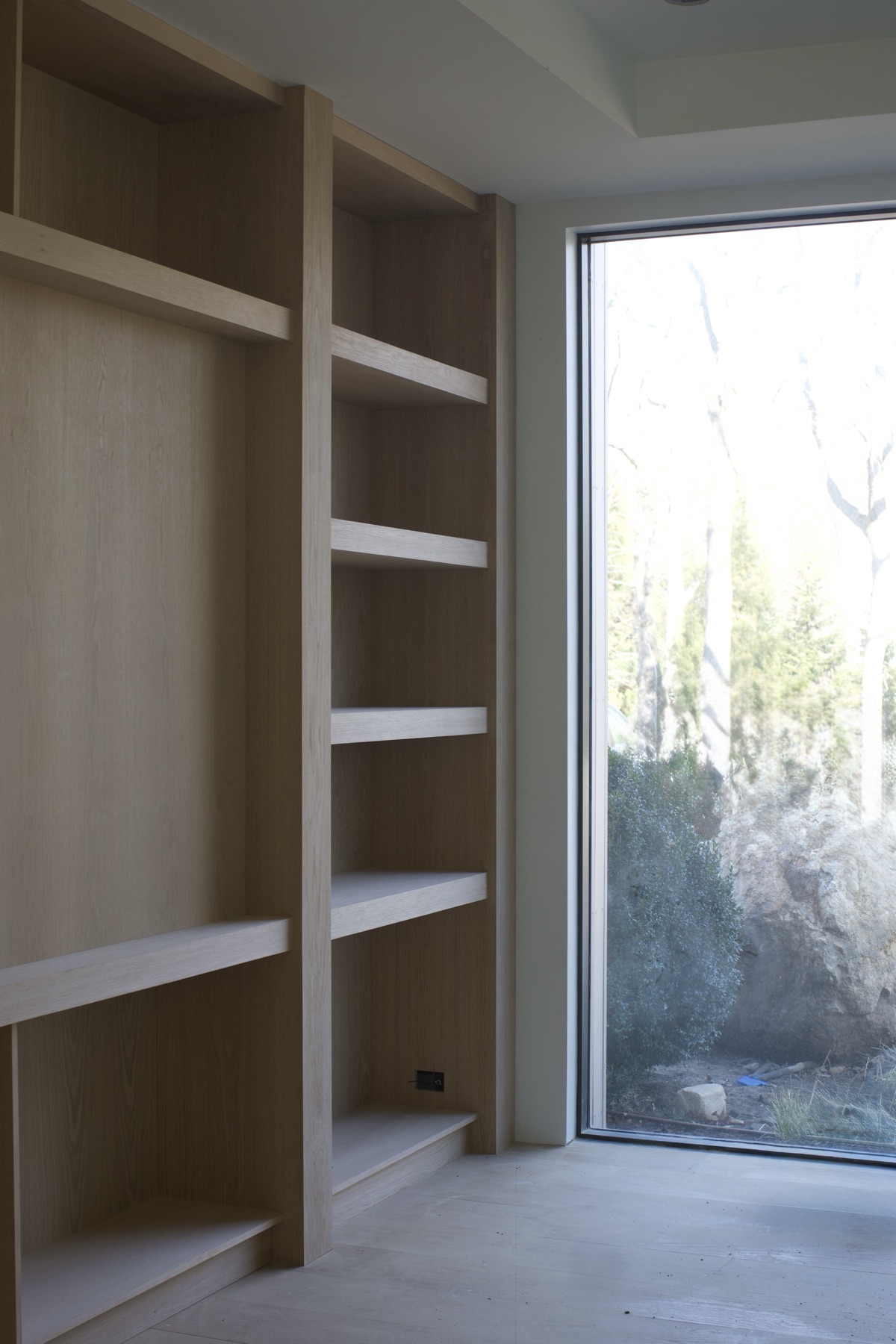 Custom white oak built-in shelving beside a picture window